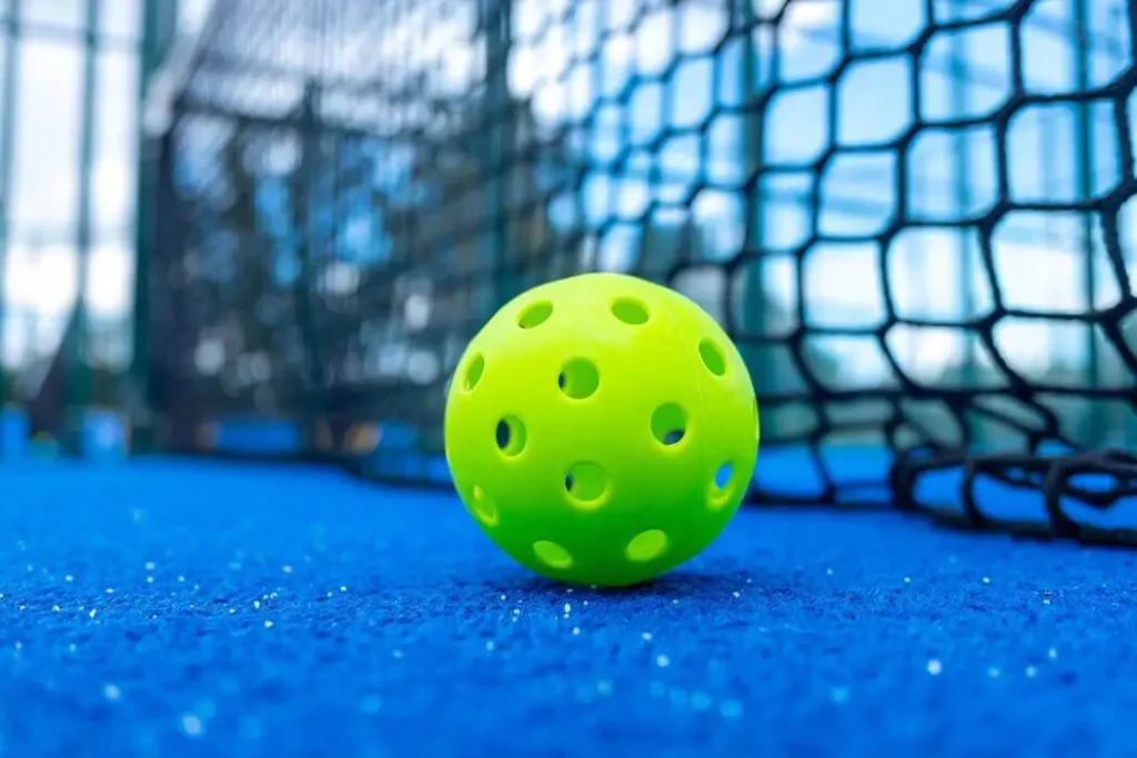 Pickleball paddles and balls resting on an outdoor court